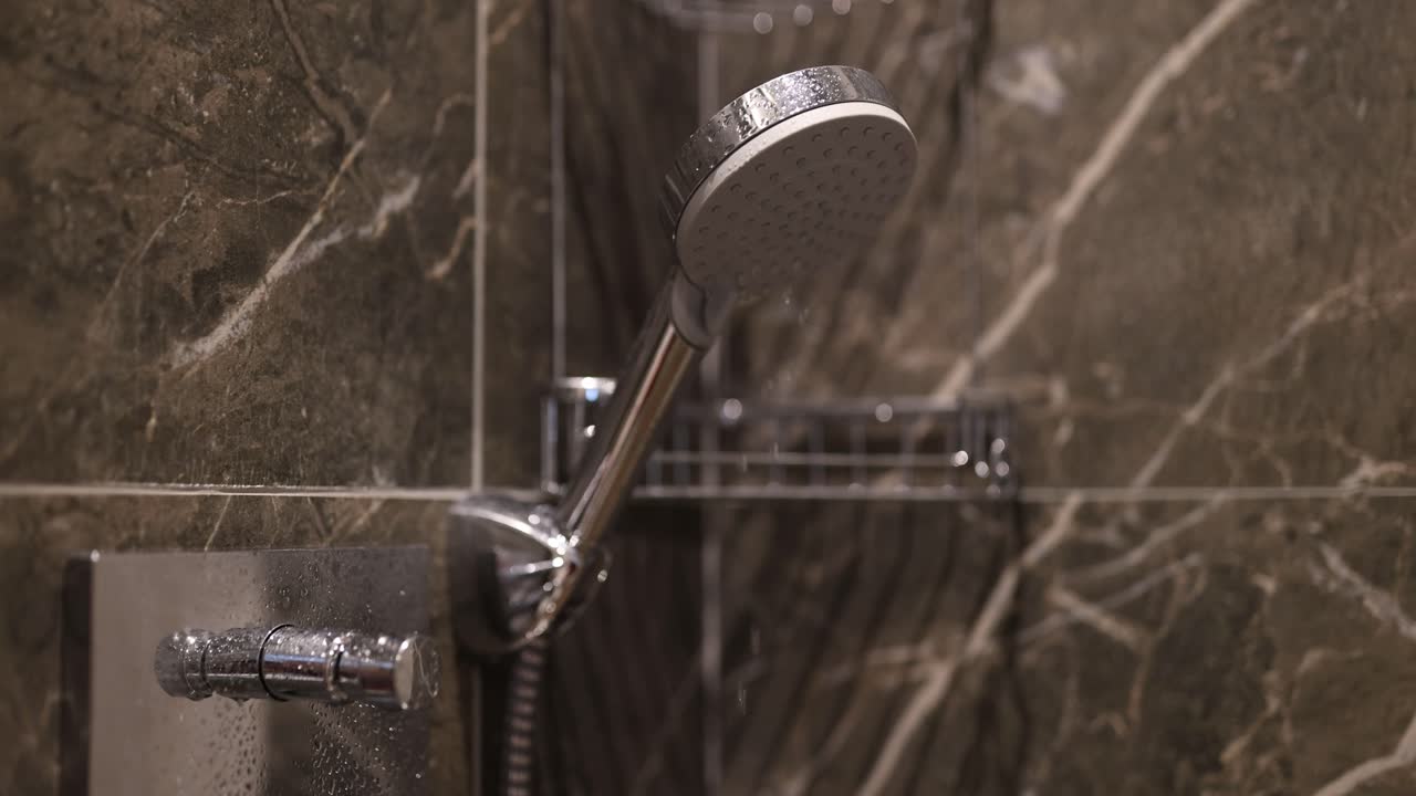 Modern shower head and faucet with water droplets in a marble bathroom