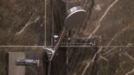 modern shower head and faucet with water droplets in a marble bathroom