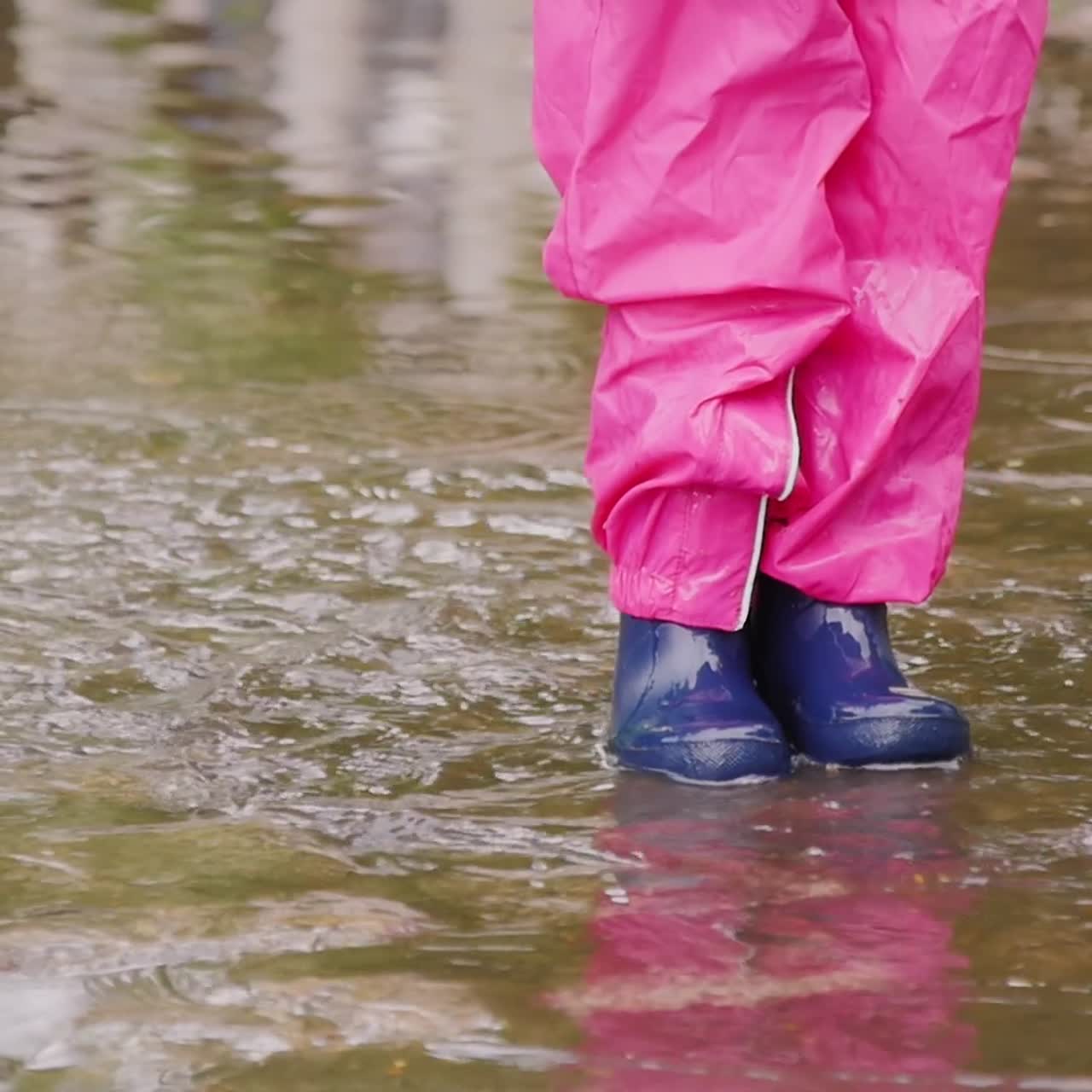 A cheerful girl jumps through puddles in the park 2