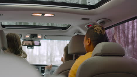 vista trasera de tres amigos felices divirtiéndose y bailando en el auto en un día de invierno