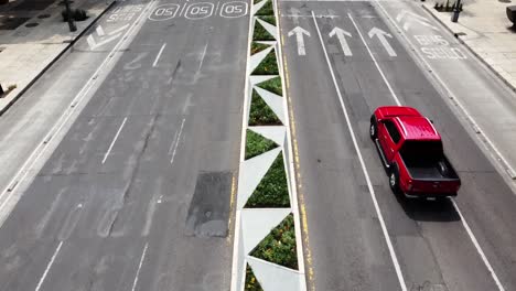 Vista-Aérea-De-Un-Camión-Rojo-En-Una-Avenida-Principal-Y-Un-Hombre-En-El-Cruce-De-Peatones