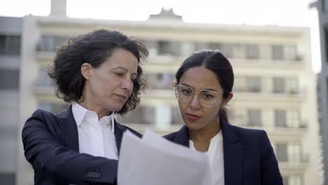 mujeres de negocios sonrientes discutiendo papeles
