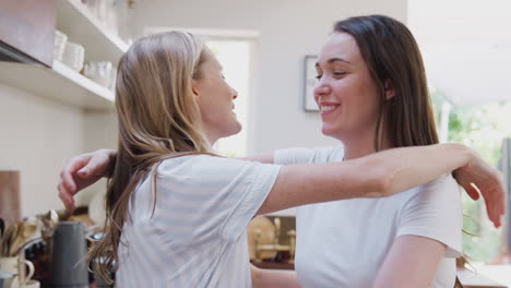 loving female gay couple hugging at home in kitchen