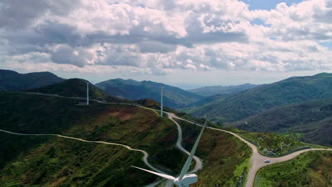 aerial flyover wind farm in rural mountain landscape during cloudy day outdoors in nature