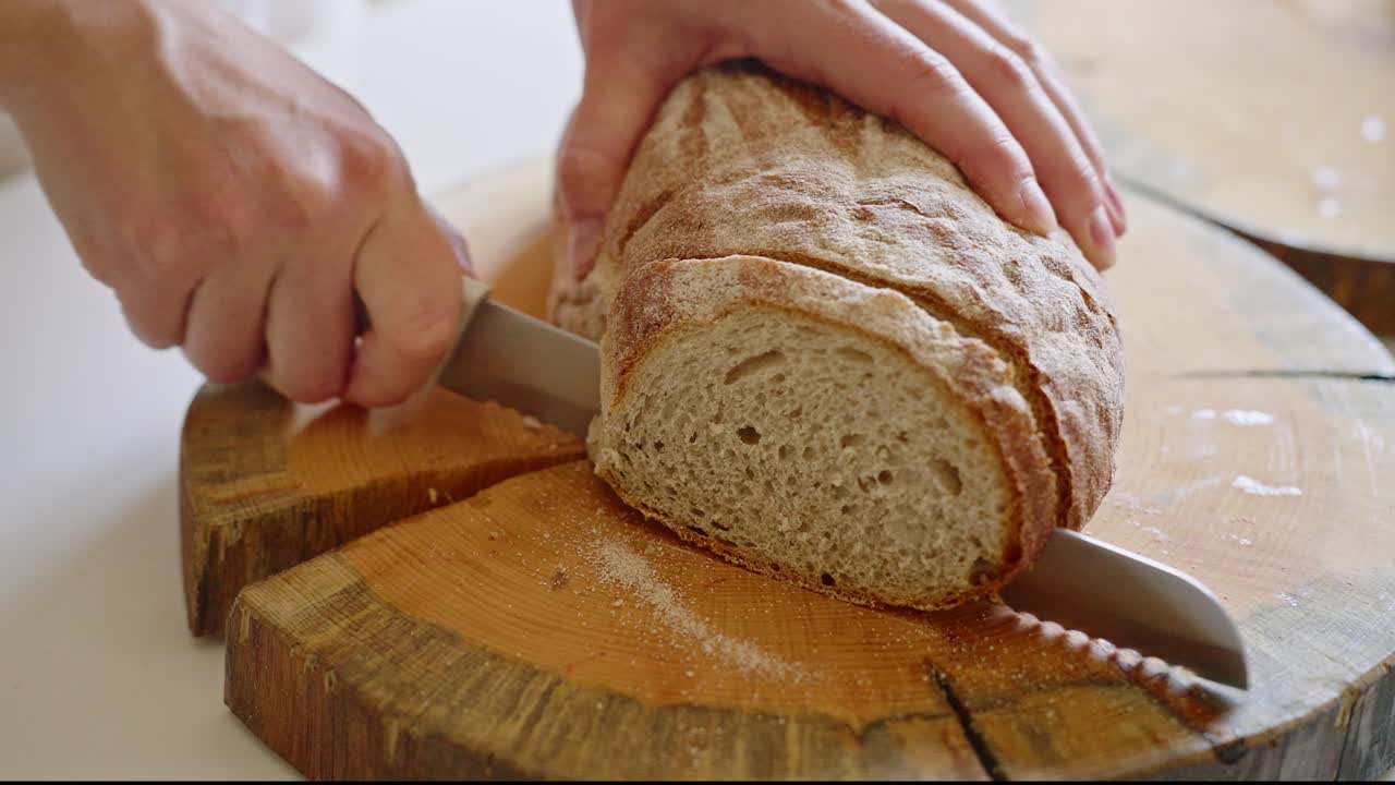 Slicing a Loaf of Bread on a Wooden Cutting Board