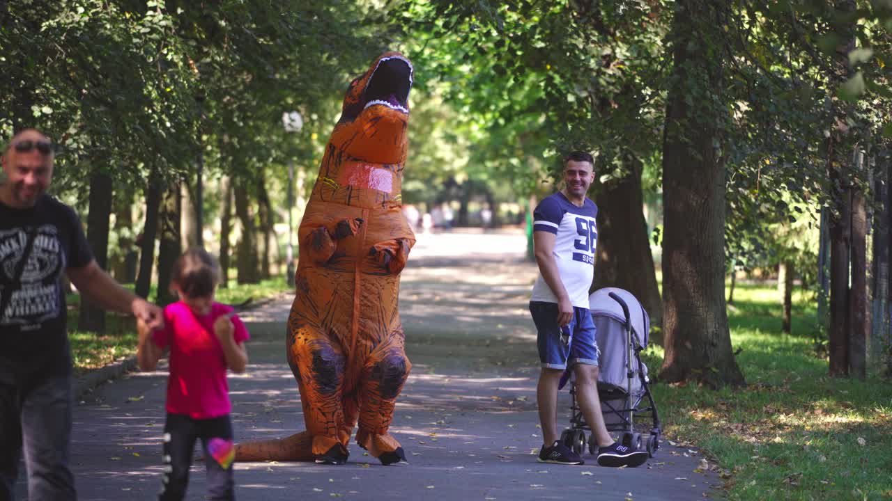 Funny inflatable dinosaur costume. Man in dinosaur costume walking in park