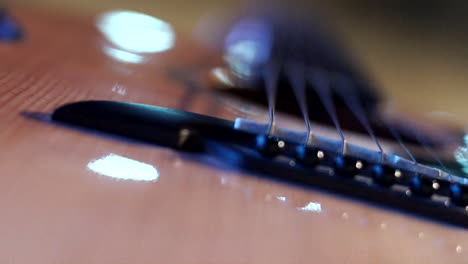 a big close up of a bass guitar strings with its base, light reflections and focus shifting on the guitar