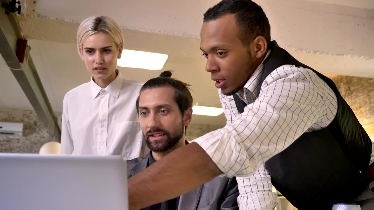 Three multy-ethnic workers discuss idea on laptop, coworking concept, communication concept