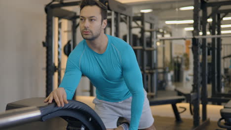 un ejercicio de fila de pesas de un solo brazo con un hombre en forma europeo en un gimnasio de entrenamiento