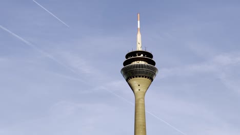 Düsseldorf,-Germany---TV-tower-of-Düsseldorf-with-plane-crossing-the-sky-above-the-city-center-of-Düsseldorf---blue-sky