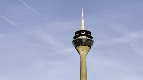 düsseldorf, germany - tv tower of düsseldorf with plane crossing the sky above the city center of düsseldorf - blue sky