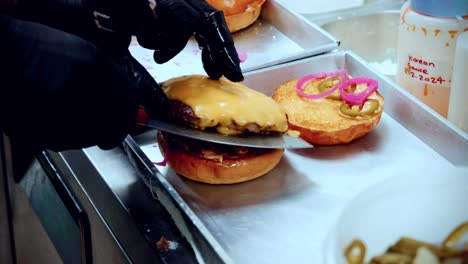 4K-Cinematic-food-cooking-footage-of-a-chef-preparing-and-making-a-delicious-homemade-burger-in-a-restaurant-kitchen-in-slow-motion-by-placing-the-cheese-burger-onto-the-bun