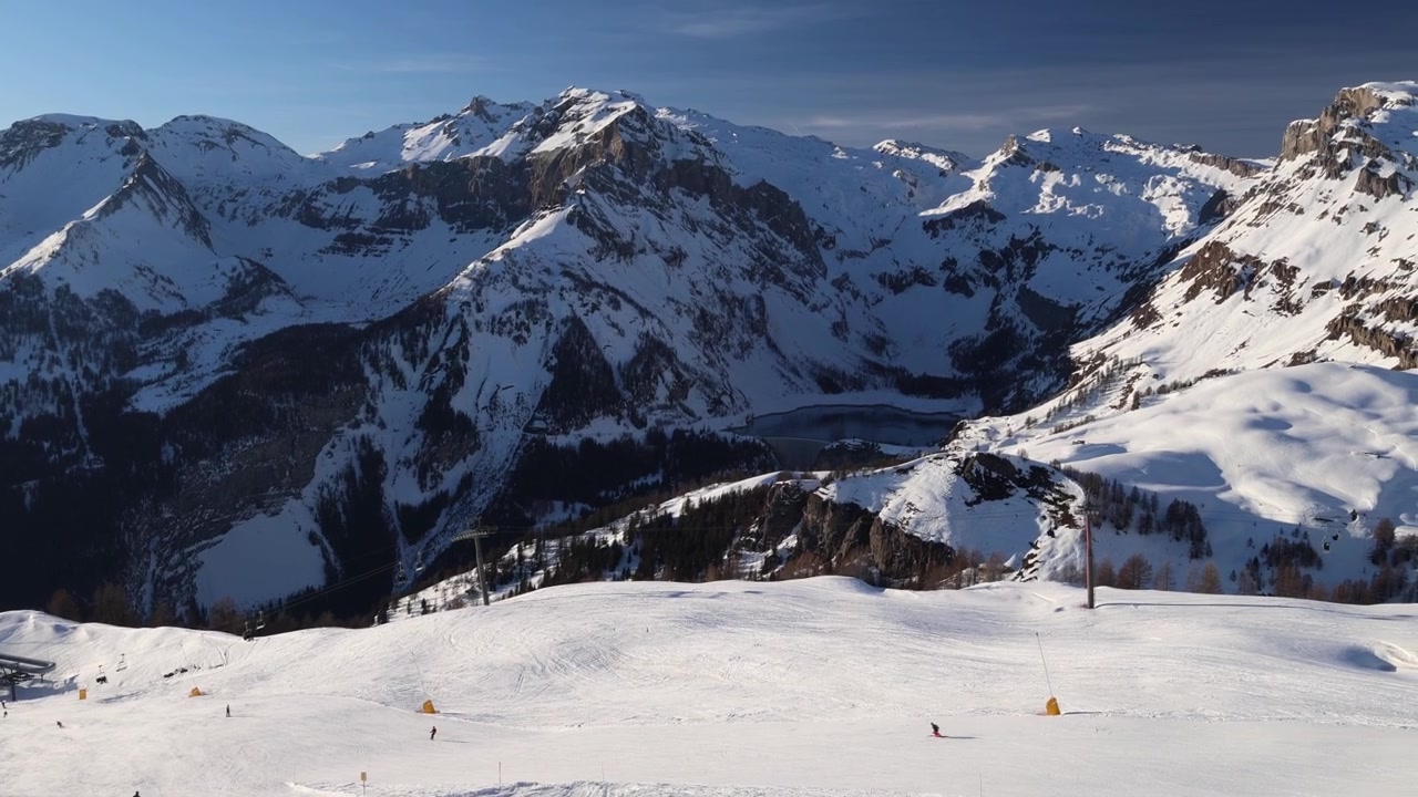Persone che sciano su una pista da sci vicino a un lago di montagna nelle Alpi svizzere