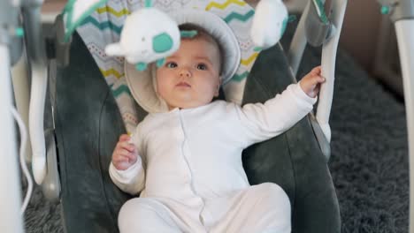 close-up front view of a pretty baby girl swinging in a swing