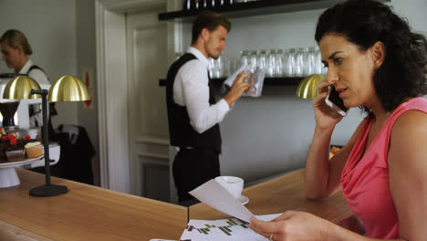 Mujer-Sentada-En-La-Barra-Del-Bar-Hablando-Por-Teléfono-Móvil