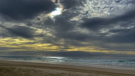 storm clouds gather at dawn over the pacific ocean, while the sun attempts to break through the clouds