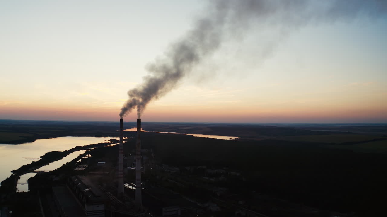 Factory tubes on the sunset background. Smoke from the pipes. Pollution concept. Video from the air.