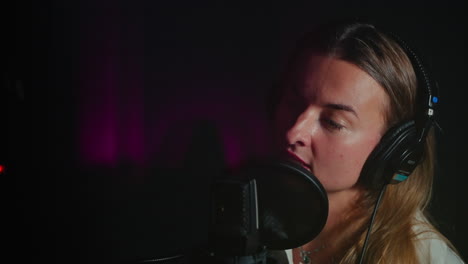 mujer cantando en un micrófono en un estudio de grabación