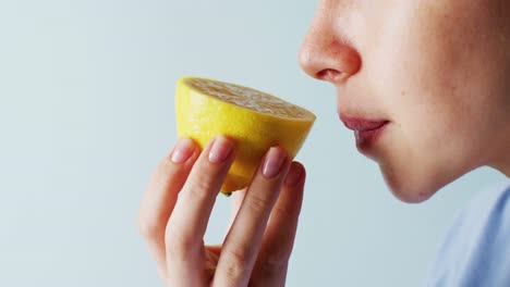 video close up detail of caucasian woman smelling half cut lemon, with blue copy space