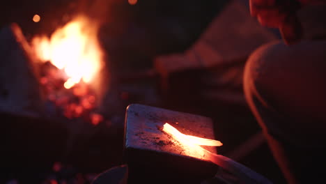 nighttime metal forging by campfire