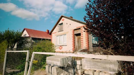 Ein-Grau-orangefarbenes-Backsteinhaus-Mit-Im-Garten-Verstreuten-Betonsteinen,-Was-Auf-Laufende-Renovierungsarbeiten-Hinweist