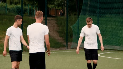 grupo de jóvenes futbolistas entrenando y pasándose el balón entre ellos en un campo de fútbol callejero en un día soleado 6