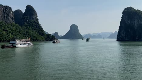 Following-Junk-Boats-through-Rock-formations-Halong-Bay,-Vietnam