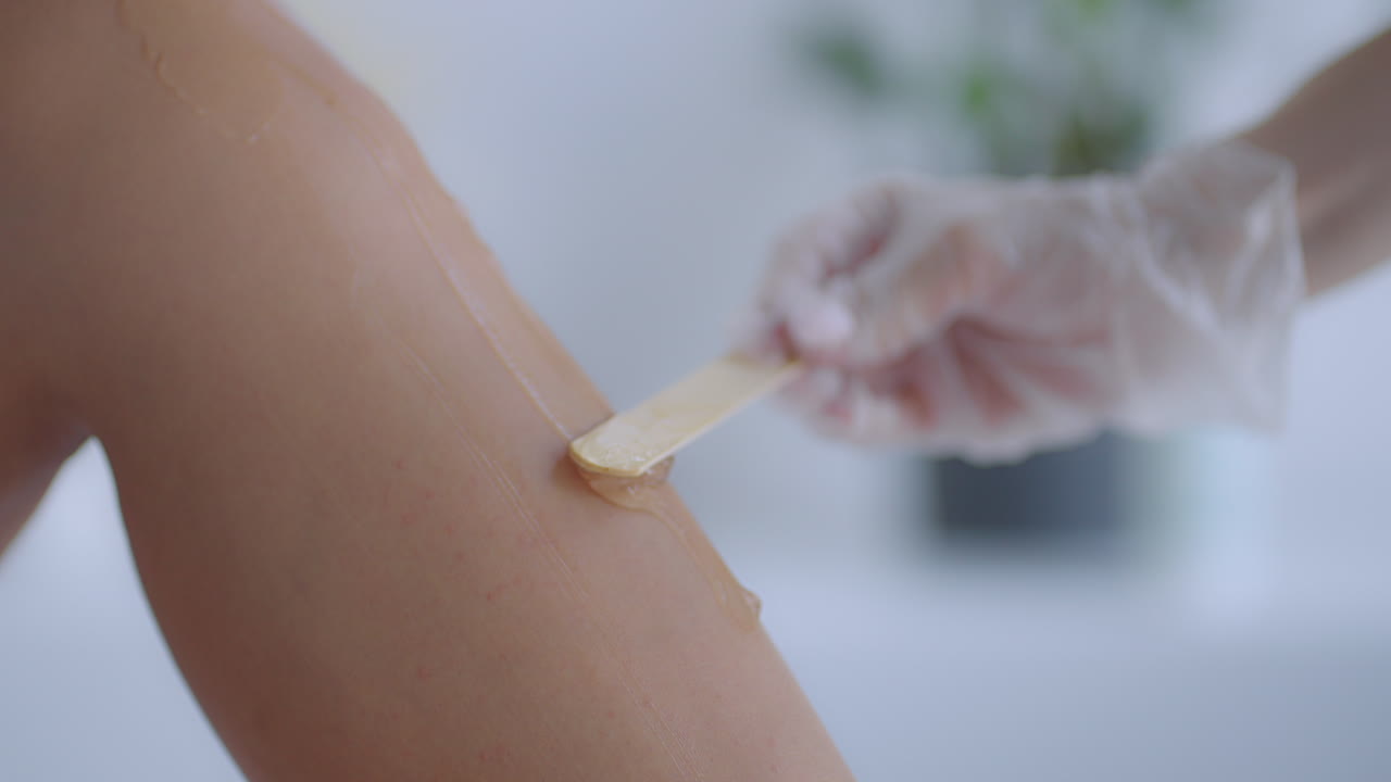 Use a stick to apply a moisturizing gel on the client's legs before laser hair removal on the legs. The doctor prepares his legs for laser hair removal in a beauty salon