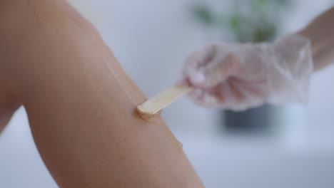 use un palo para aplicar un gel hidratante en las piernas del cliente antes de la depilación láser en las piernas. el médico prepara sus piernas para la depilación láser en un salón de belleza
