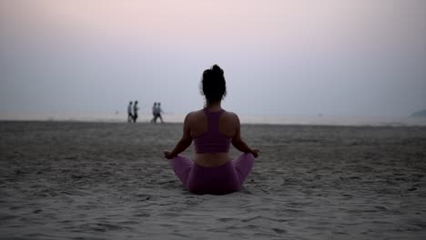 Indian-Yoga-Woman-in-Lotus-Pose,-Meditates-at-beach-at-Sunrise,-Sunset