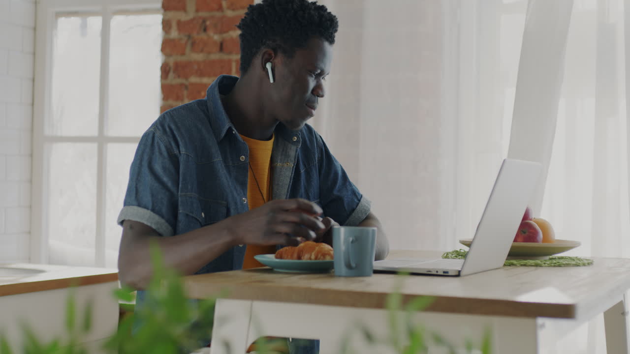 Man working from home, eating breakfast and listening to music