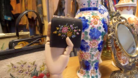 a wooden artificial hand holds a wallet, colorful vases in the background