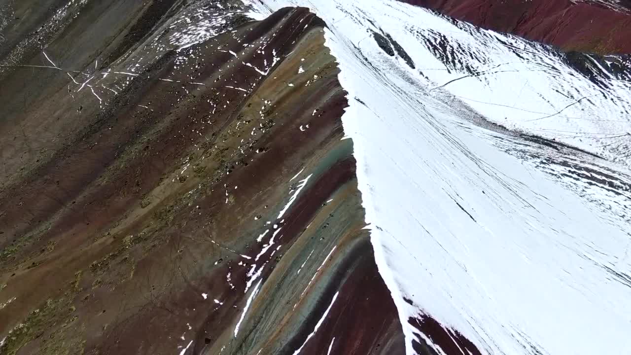 vista de avión no tripulado en perú volando sobre la montaña arco iris en cuzco, mostrando a la gente mirando fijamente la cordillera mitad nevada mitad coloreada