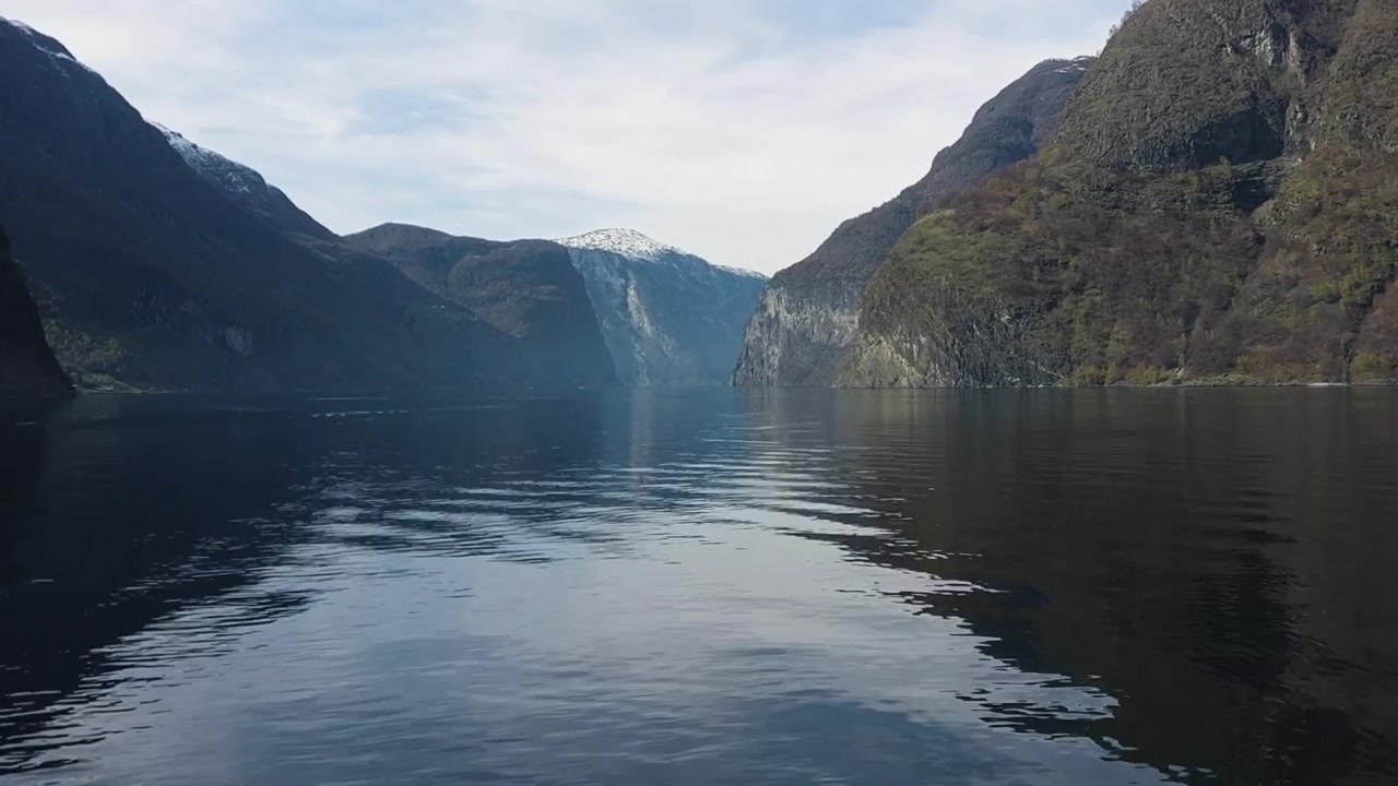 Zeitraffer: Boot fährt durch ruhige Fjordgewässer zwischen steilen Bergklippen