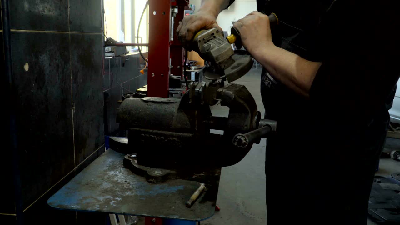 Closeup of worker using a grinder cuts metal in a workshop