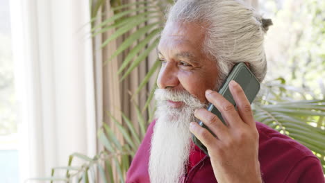 Feliz-Hombre-Mayor-Birracial-Con-Barba-Blanca-En-Un-Teléfono-Inteligente-En-Una-Habitación-Soleada,-Espacio-Para-Copiar,-Cámara-Lenta