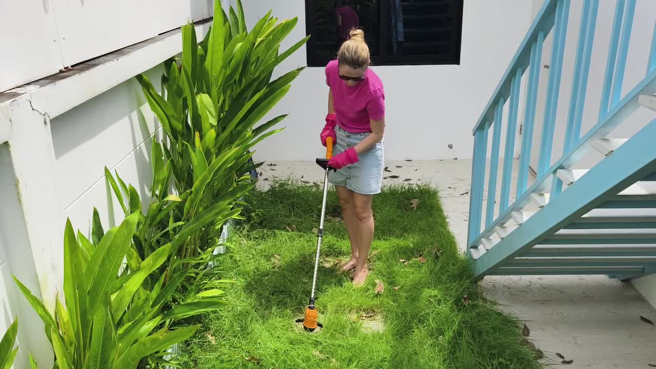 mujer recortando el césped en un jardín del patio trasero