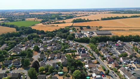 aerial footage of the small suffolk village of acton surrounded by farmland and golden fields