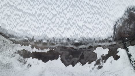 slow descend aerial bird's eye view of windswept ice covered snow lake in suwalki gap masuria poland