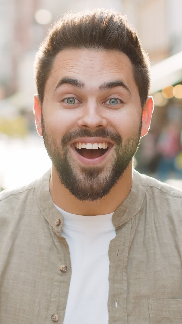 Joven mirando sorprendido a la cámara conmocionado por la repentina victoria buenas noticias de victoria wow en la calle de la ciudad