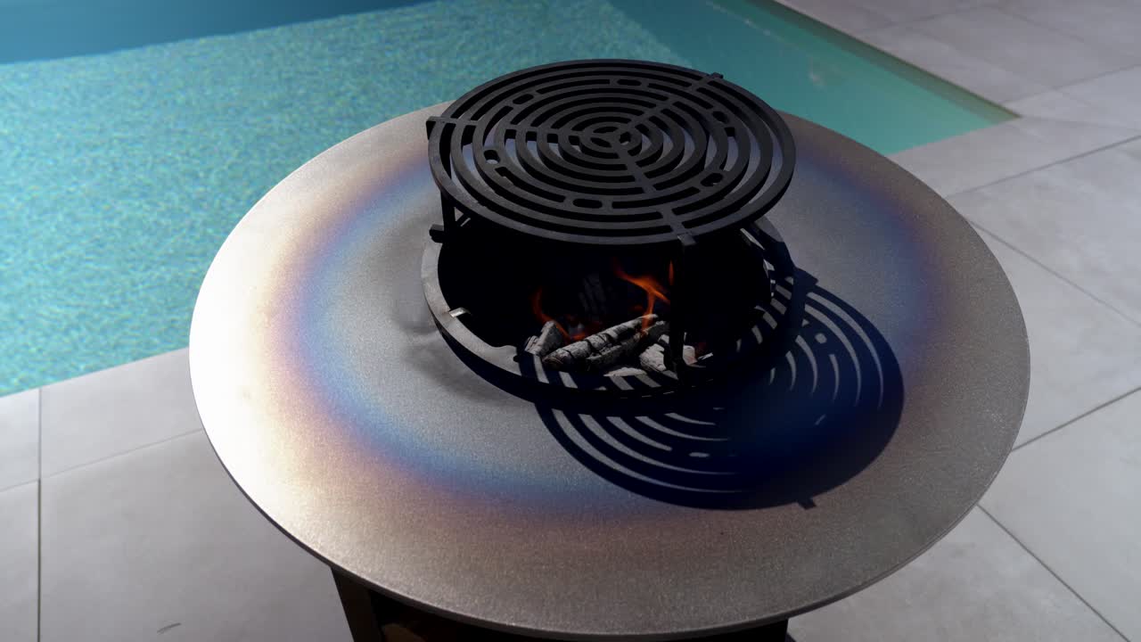 Vidvinkelvy av metall-brasero med brinnande eld och grill ovanför