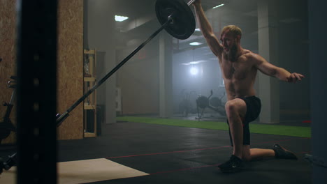 a male athlete lifts a weight bar with one hand in slow motion. strength training for a boxer. the man is sweating working out in the gym practicing the force of the blow with his hand