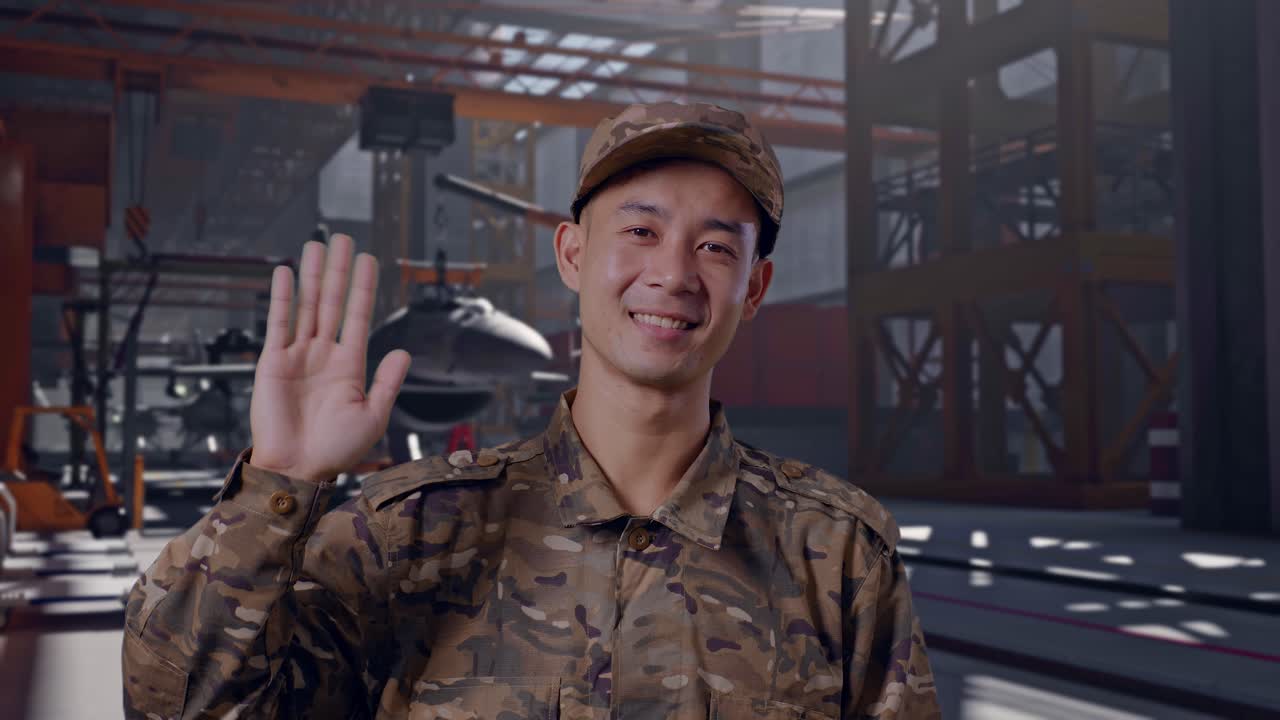 Soldato asiatico sorridente in uniforme che saluta in un hangar per aeromobili