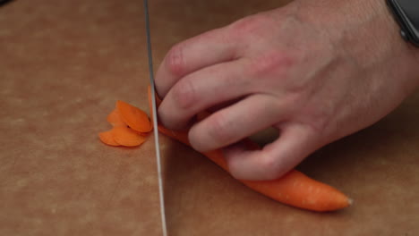 hands cutting carrot into thin slice