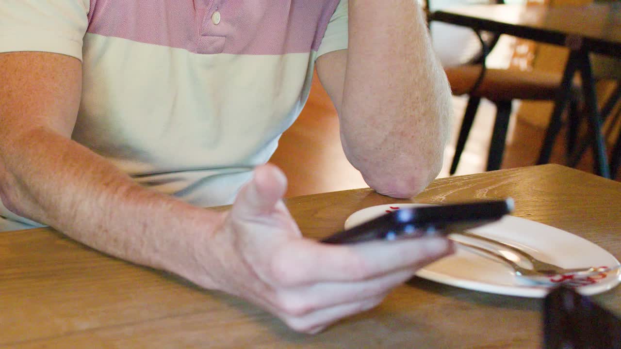 Man interacts with smartphone while waiting for meal at casual Bangkok restaurant, natural lighting