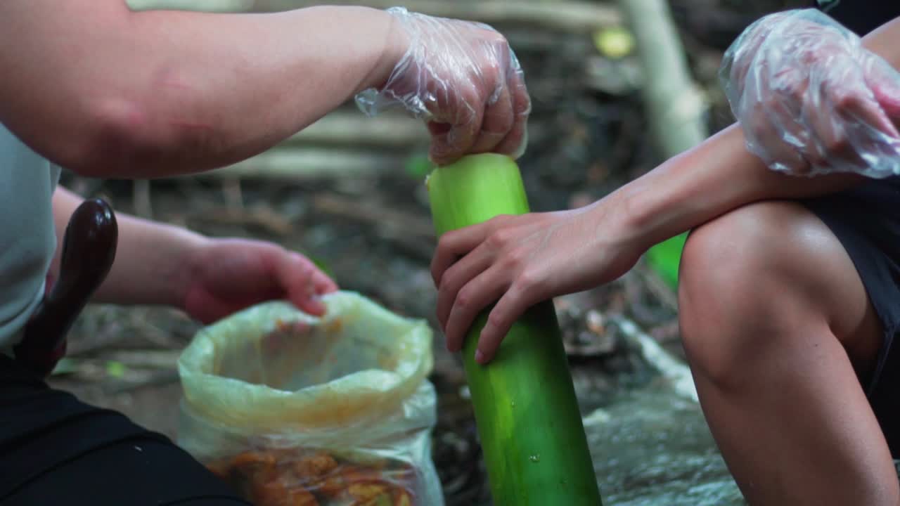 Campers stuffing the food into the bamboo shoot to be ready to cook