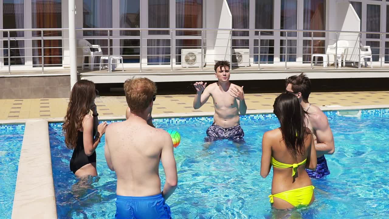 grupo de jóvenes amigos jugando voleibol en la piscina 1