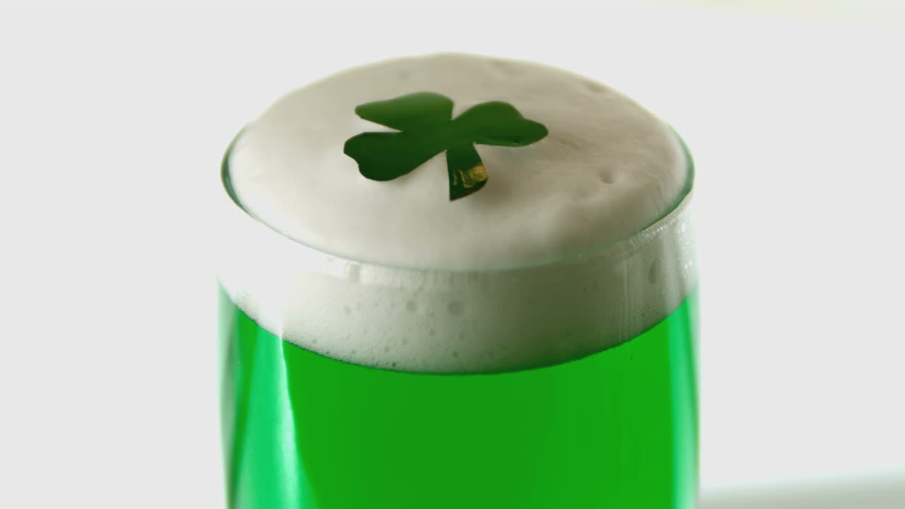 Shamrock confetti falling on pint of green beer