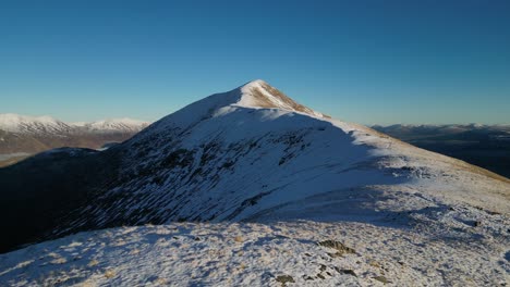 el pico de la montaña nevada en escocia glen kingie sgurr un fhuarain aérea