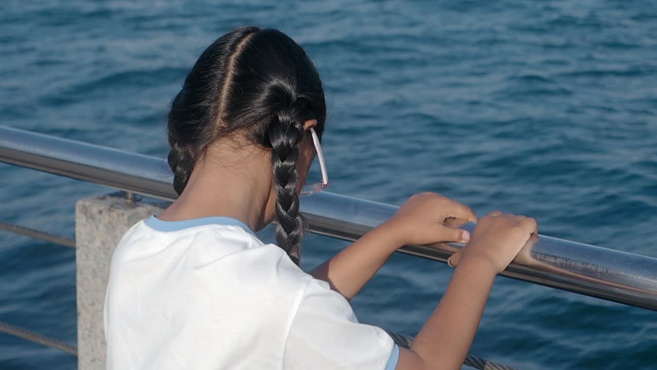 Young girl with braids looking out at the ocean